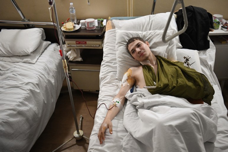 A 19 year old Ukrainian soldier named Yevhen lays in bed in a military hospital in Lviv on March 1, 2022, after being injured by a mine in the Luhansk region. (Photo by Daniel LEAL / AFP)