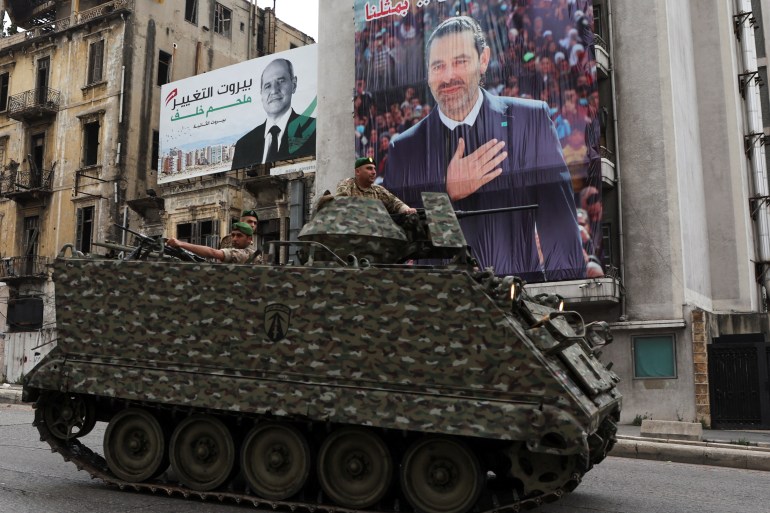 Army soldiers drive past a poster depicting Lebanon's former Prime Minister Saad al-Hariri, on the eve of the parliamentary election, in Beirut, Lebanon May 14, 2022. REUTERS/Mohamed Azakir