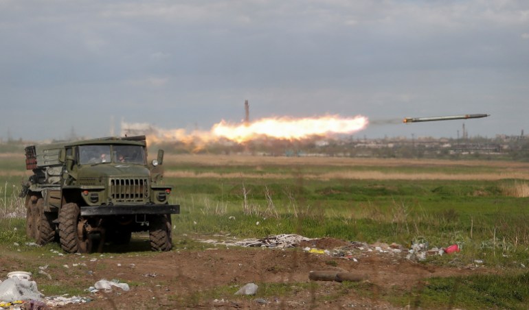 Service members of pro-Russian troops fire a BM-21 Grad multiple rocket launch system in Mariupol