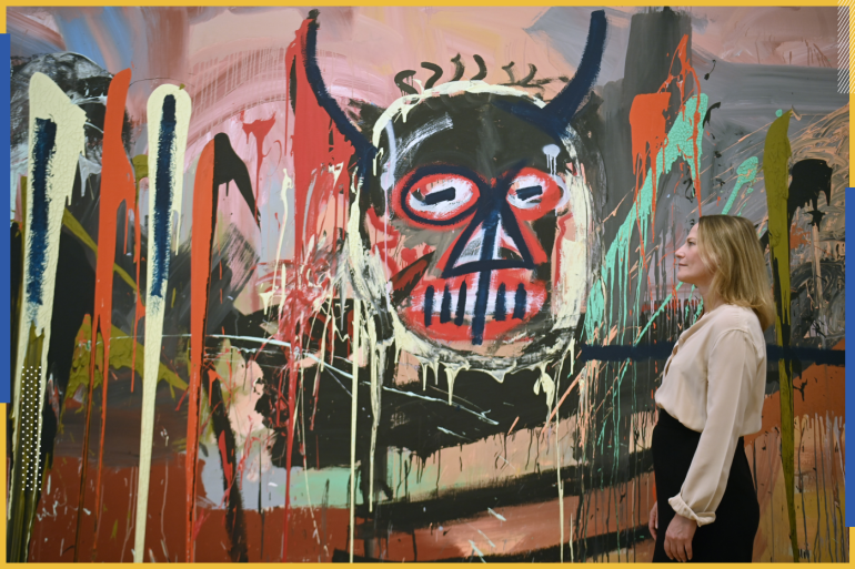 epa09791809 Cheyenne Westphal (R), the Phillips Global Chairwoman, poses with the work 'Untitled' (1982) by US artist Jean-Michel Basquiat at the Phillips auction house in London, Britain, 28 February 2022. The large size painting is estimated in the region of 70 million US dollars. The auction will take place on 18 May 2022 in New York. EPA-EFE/NEIL HALL