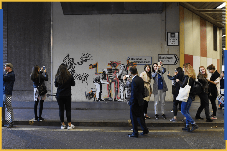 epa06212317 Londoners take photographs of a graffiti artwork by the elusive street artist Banksy, in London, Britain, 18 September 2017. Street artist Banksy depicted the work of Jean-Michel Basquiat with two new murals in London near the Barbican where a new exhibition of the late US artist will open this week. EPA-EFE/FACUNDO ARRIZABALAGA