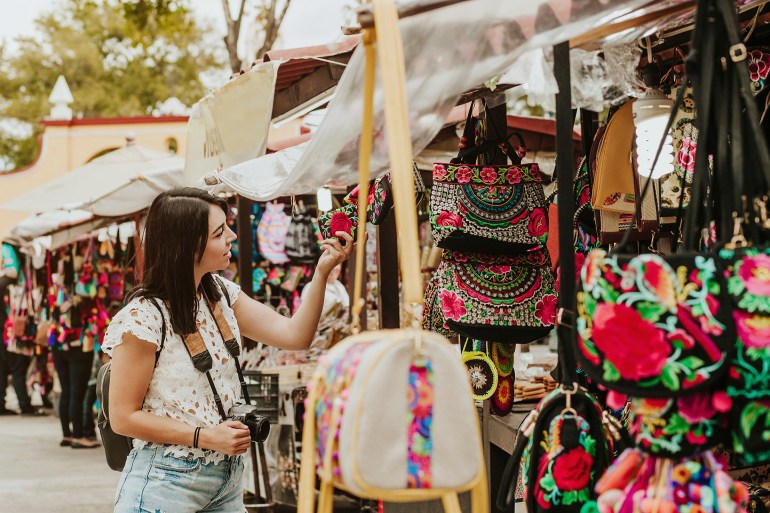 traveler girl buying souvenirs in the traditional Mexican market in Mexico streets, hispanic tourists standing in outdoor