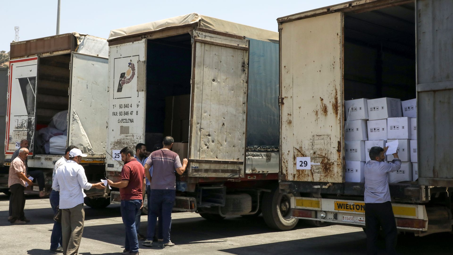 People stand near trucks loaded with humanitarian aid at Bab al-Hawa crossing at the Syrian-Turkish border, in Idlib governorate