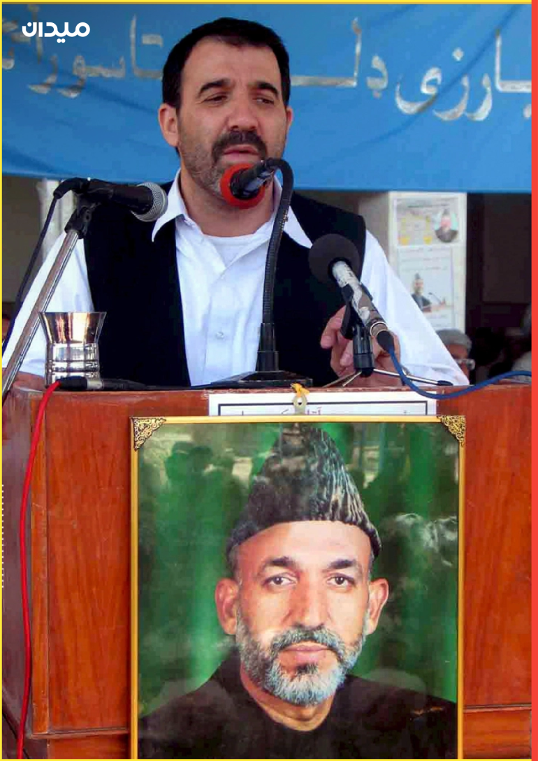 أحمد والي كرزاي يتحدث، وهو شقيق الرئيس الأفغاني حامد كرزاي (في الصورة على اللافتة) في قندهار.