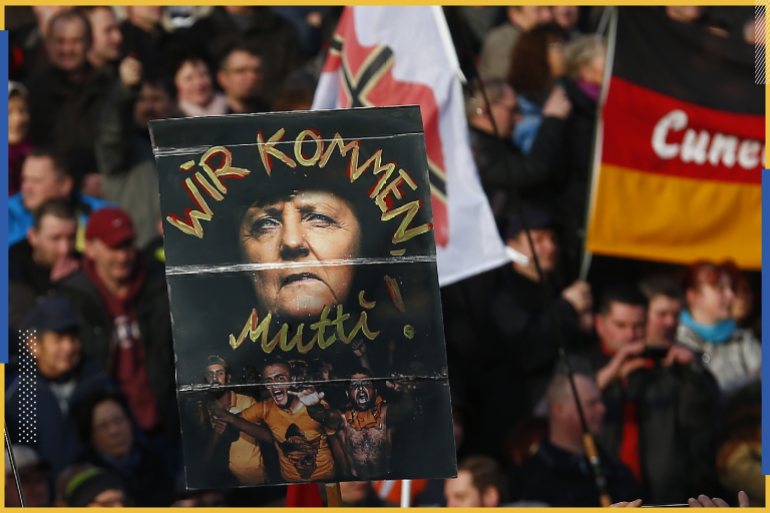 أنصار حركة الأوروبيون المسالمون ضد أسلمة الغرب (pegida) يحملون ملصق يصور المستشارة الألمانية أنجيلا ميركل مع نص مكتوب عليه "نحن قادمون يا أمي!" خلال مظاهرة في ألمانيا 2016 (رويترز)