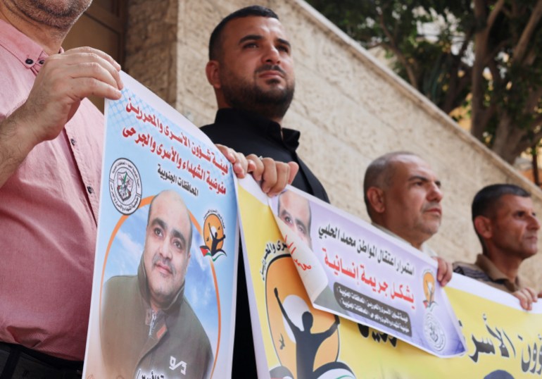 People hold pictures of Mohammad El Halabi, during a solidarity gathering following an Israeli court decision to sentence him for 12 years, outside the office of the International Committee of the Red Cross in Gaza City