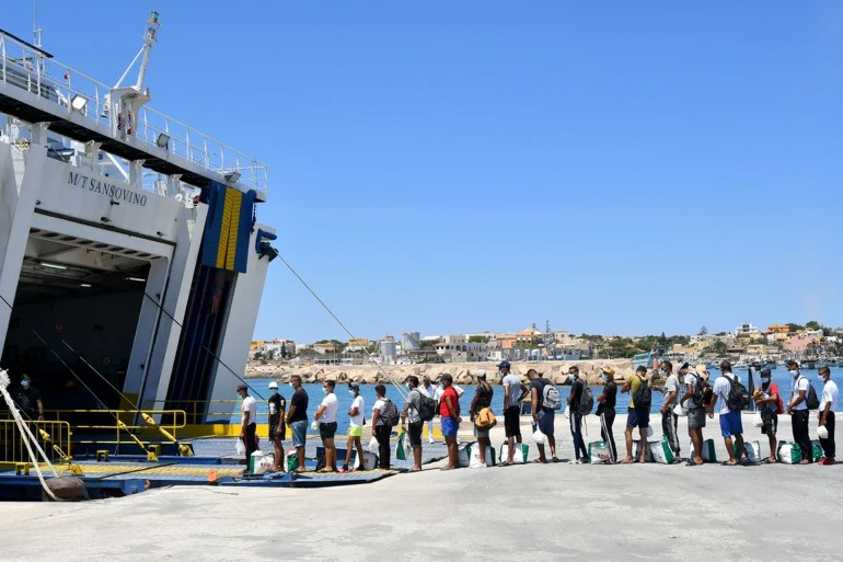 Migrants escorted by Italian authorities queue to board a ferry from the island of Lampedusa to SicilyALBERTO PIZZOLI/AFP