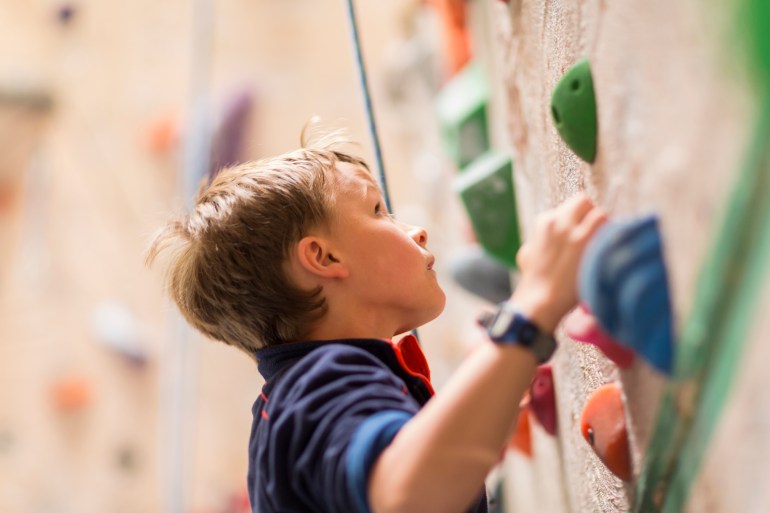 Caucasian boy climbing rock wall indoors GettyImages-565889499