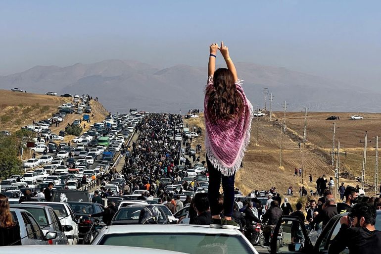 This UGC image posted on Twitter reportedly on October 26, 2022 shows an unveiled woman standing on top of a vehicle as thousands make their way towards Aichi cemetery in Saqez, Mahsa Amini's home town in the western Iranian province of Kurdistan, to mark 40 days since her death, defying heightened security measures as part of a bloody crackdown on women-led protests. - A wave of unrest has rocked Iran since 22-year-old Amini died on September 16 following her arrest by the morality police in Tehran for allegedly breaching the country's strict rules on hijab headscarves and modest clothing. (Photo by UGC / AFP) / === RESTRICTED TO EDITORIAL USE - MANDATORY CREDIT "AFP PHOTO / UGC IMAGE" - NO MARKETING NO ADVERTISING CAMPAIGNS - DISTRIBUTED AS A SERVICE TO CLIENTS FROM ALTERNATIVE SOURCES, AFP IS NOT RESPONSIBLE FOR ANY DIGITAL ALTERATIONS TO THE PICTURE'S EDITORIAL CONTENT, DATE AND LOCATION WHICH CANNOT BE INDEPENDENTLY VERIFIED === /