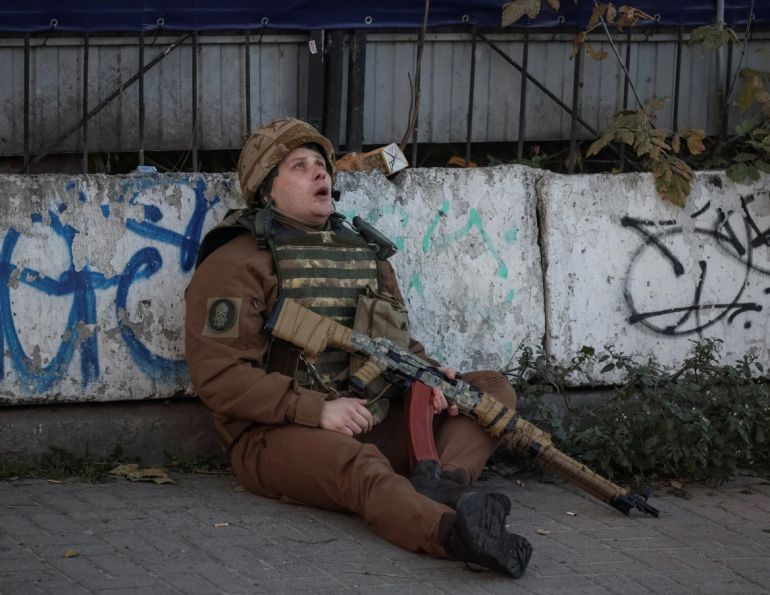 A Ukrainian serviceman takes cover during a Russian drone attack. [Gleb Garanich/Reuters