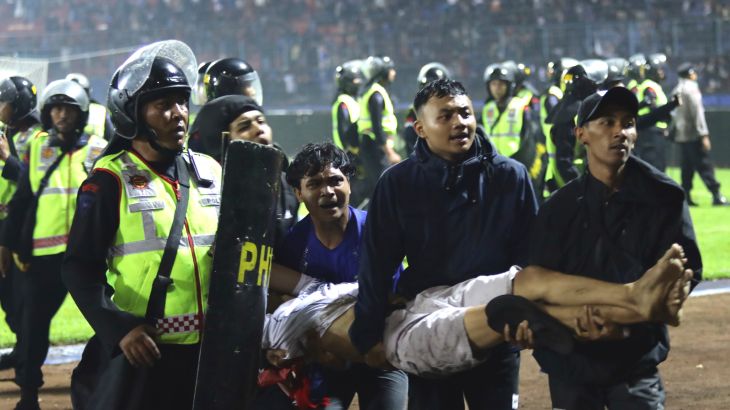 Soccer fans carry an injured man following clashes during a soccer match at Kanjuruhan Stadium in Malang, East Java, Indonesia, Saturday, Oct. 1, 2022. Panic following police actions left over 100 dead, mostly trampled to death, police said Sunday. (AP Photo/Yudha Prabowo)