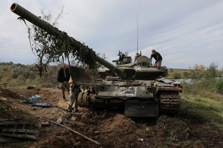 Ukrainian servicemen repair a Russian tank captured during a counteroffensive operation in Kharkiv region