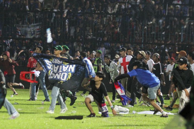 Arema FC supporters enter the field after the team they support lost to Persebaya after a football match at Kanjuruhan Stadium