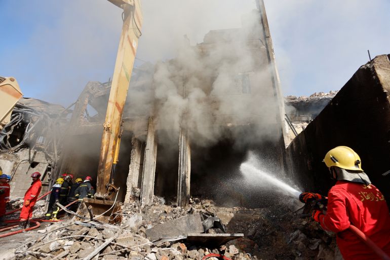Firefighters spray water at the scene of a fire at a building after the building containing perfumes stores collapsed due to the major fire, in Baghdad
