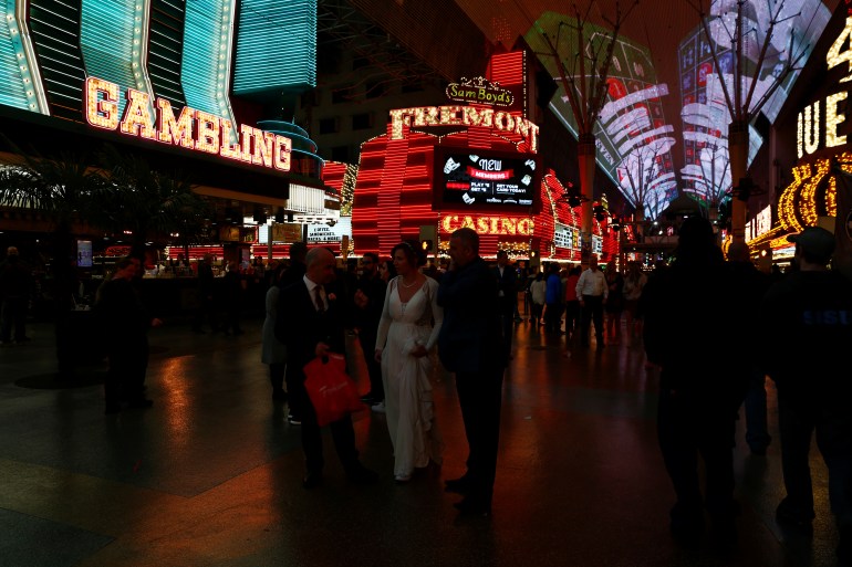 A bride and groom walk near Binion's Gambling Hall and Hotel, the Fremont Hotel and Casino and the Four Queens Hotel and Casino on Fremont Street in downtown Las Vegas
