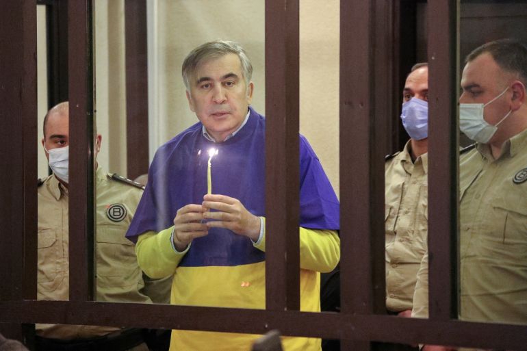 FILE PHOTO: Georgian former President Mikheil Saakashvili, who was convicted in absentia of abuse of power during his presidency and arrested upon his return from exile, holds a candle while praying for Ukraine in a defendant's dock during a court hearing in Tbilisi, Georgia, March 17, 2022. REUTERS/Irakli Gedenidze/File Photo