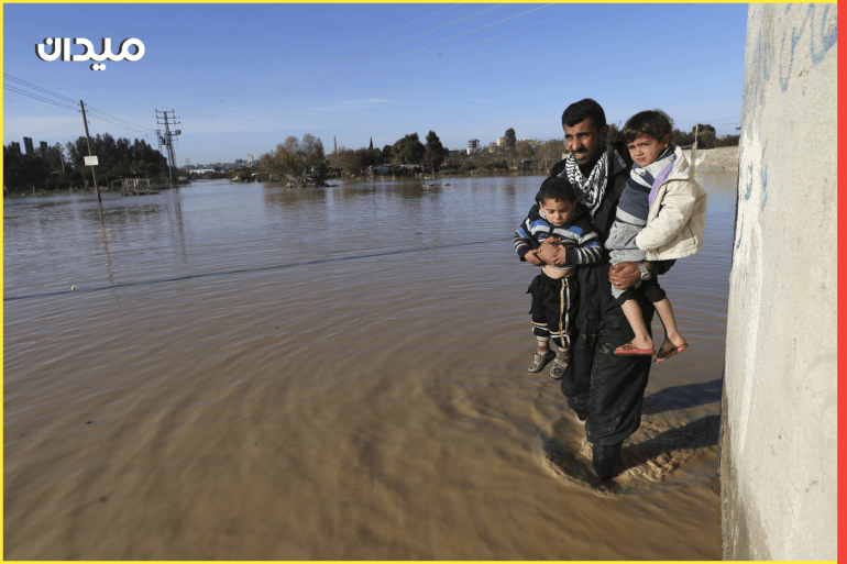 A Palestinian man carries children as he evacuates them in the village of Al-Moghraga after it was flooded by rain water, near central Gaza Strip February 22, 2015. REUTERS/Ibraheem Abu Mustafa (GAZA - Tags: ENVIRONMENT)