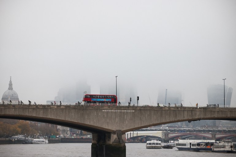 People walk over Waterloo Bridge during foggy weather in London
