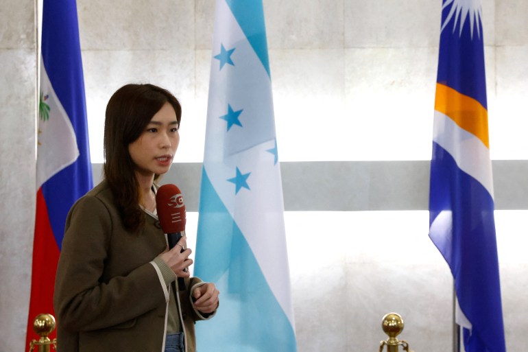 A Taiwanese news anchor speaks infront of an Honduras flag display at the Ministry of Foreign Affairs in Taipei