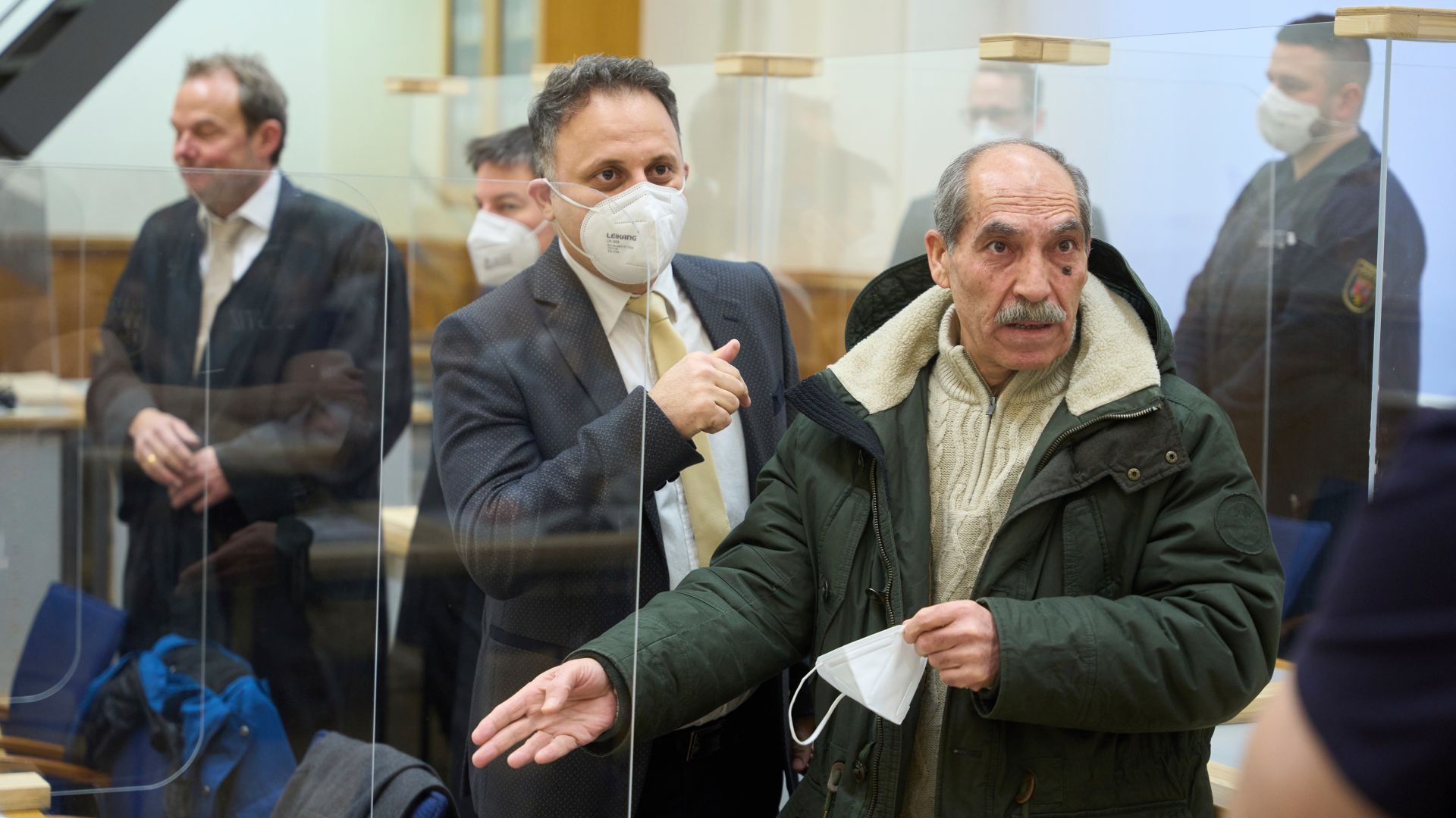 The defendant, Anwar Raslan, right, stands in the courtroom before the pronouncement of the verdict at the Higher Regional Court in Koblenz, Germany, Thursday, Jan. 13, 2022. A German court has convicted the former Syrian secret police officer of crimes against humanity for overseeing the abuse of detainees at a jail near Damascus a decade ago. The verdict Thursday in the landmark trial has been keenly anticipated by Syrians who suffered abuse or lost relatives in the country's long-running conflict. (Thomas Frey/Pool via AP)