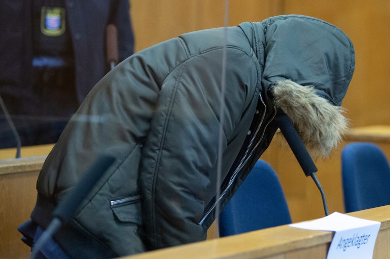 A view of an unidentified Syrian doctor after he was led into the security room of the Higher Regional Court, in Frankfurt, Germany, Wednesday, Jan. 19, 2022. A court in Germany will begin hearing a case against a Syrian doctor accused of crimes against humanity for torturing and killing inmates at a government-run prison in his home country. Federal prosecutors say the doctor worked at a military intelligence prison in the Syrian city of Homs from April 2011 until late 2012. Prosecutors accuse him of killing one person and torture in 18 cases. (Boris Roessler/Pool Photo via AP)