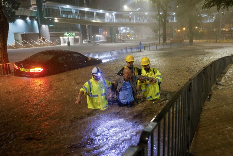 عمال يساعدون سائقا تقطعت به السبل بسبب الفيضانات في هونغ كونغ (رويترز)