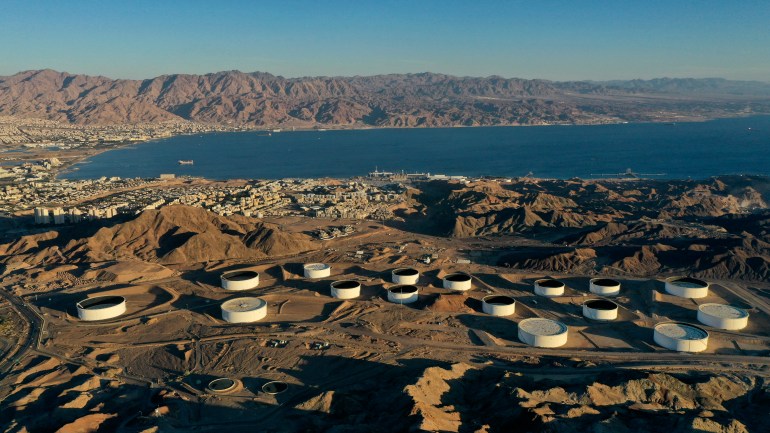 This picture taken on February 10, 2021 shows an aerial view of (foreground) oil storage containers of the Eilat Ashkelon Pipeline Company (EAPC) in the mountains near Israel's Red Sea port city of Eilat (C-L), and (background) the Jordanian coastline south of Aqaba (top L). - Israeli environmentalists are warning that the UAE-Israeli deal to bring Emirati crude oil by tanker to a pipeline in Eilat threatens unique Red Sea coral reefs and could lead to "the next ecological disaster". The deal was signed after Israel and the UAE normalised ties late in 2020, and should come into force within the next few months. (Photo by MENAHEM KAHANA / AFP)
