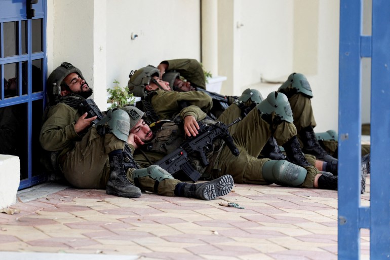 Israeli soldiers rest near a building the day after a mass infiltration by Hamas gunmen from the Gaza Strip, in Sderot, southern Israel October 8, 2023. REUTERS/Ronen Zvulun TPX IMAGES OF THE DAY