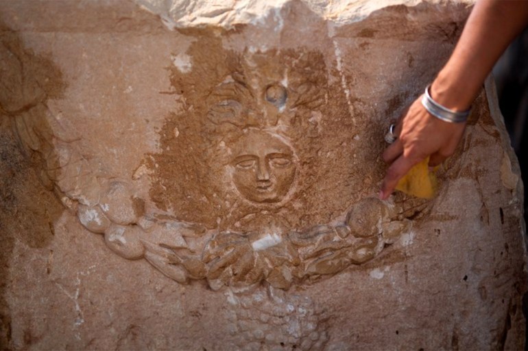 A member of the Israel Antiquities Authority (IAA) cleans the head of the monstrous mythological female figure Medusa which includes images of the venemous snakes that she was said to have as hair on a unique Roman-era sarcophagus adorned with the carving of a young man at a warehouse in Bet Shemesh on September 3, 2015. The sarcophagus, estimated 1,800 years old with exquisite carvings of Greco-Roman mythological figures, was found, removed and concealed by workers at a construction site in southern Israeli coastal city Ashkelon before the IAA discovered the ancient artefact damaged. AFP PHOTO / MENAHEM KAHANA (Photo credit should read MENAHEM KAHANA/AFP via Getty Images)