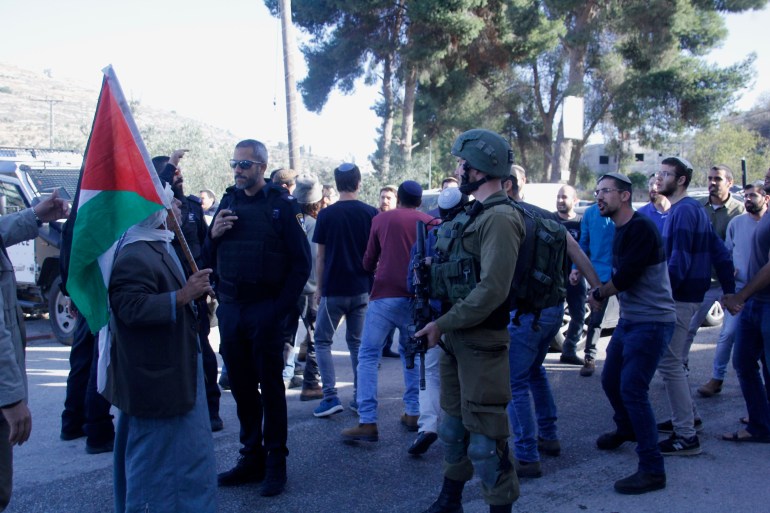 مستوطنون يستفزون المواطنين الفلسطينيين برقصاتهم في قرية اللبن جنوب نابلس بحماية جيش الاحتلال (الجزيرة)