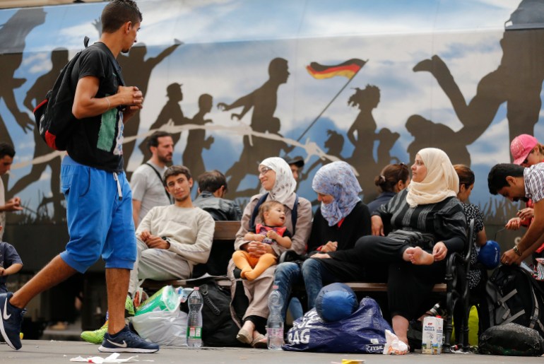 Migrants wait in front of a painted train at the railway station in Budapest, Hungary, Thursday, Sept. 3, 2015. Over 150,000 migrants have reached Hungary this year, most coming through the southern border with Serbia, and many apply for asylum but quickly try to leave for richer EU countries.(AP Photo/Frank Augstein)