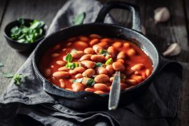 Baked beans with herbs and tomato sauce in iron dish