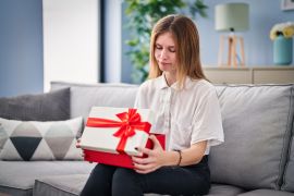 Beautiful woman holding gift depressed and worry for distress, crying angry and afraid. sad expression. ; Shutterstock ID 2214299143; purchase_order: aljazeera ; job: ; client: ; other: