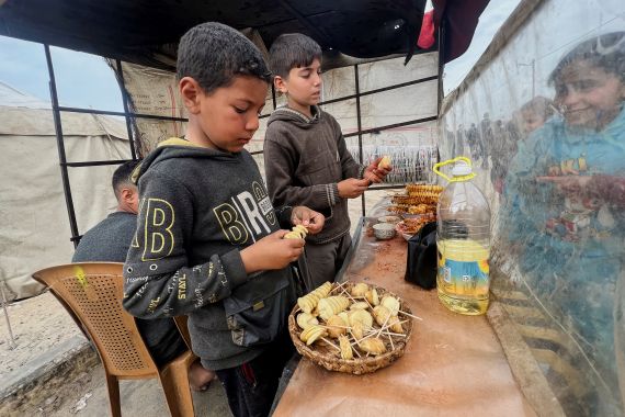 Displaced Palestinian boys sell homemade potato chips outside a tent camp, amid the ongoing conflict between Israel and Hamas, in Rafah in the southern Gaza Strip, February 13, 2024. REUTERS/Saleh Salem