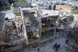 فلسطينيون يقفون إلى جانب منزل دمرته غارة جوية إسرائيلية في رفح جنوب قطاع غزة (رويترز)