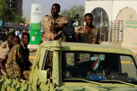 سودانيون أثناء مرورهم بمجمع وزارة الدفاع بالخرطوم (رويترز)