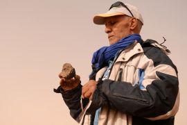 A meteorite hunter examines a rock near the oasis town of Mhamid el-Ghizlane, in southern Morocco&#039;s Sahara desert province of Zagora on March 25, 2018. Equipped with a &quot;very strong&quot; magnet and magnifying glass, retired physical education teacher Mohamed Bouzgarine says that discoveries &quot;can be more valuable than gold&quot;. (Photo by FADEL SENNA / AFP) (الفرنسية)