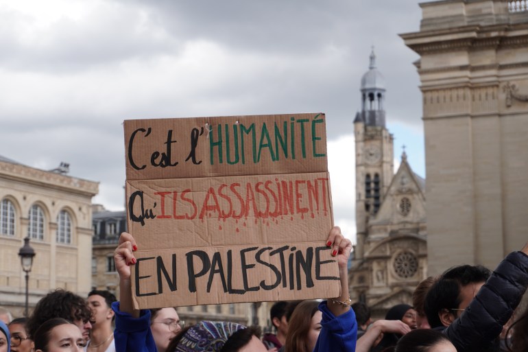 لافتة تحملها طالبة كُتب عليها "يغتالون الإنسانية في فلسطين"، في ساحة البانثون في باريس، الجمعة