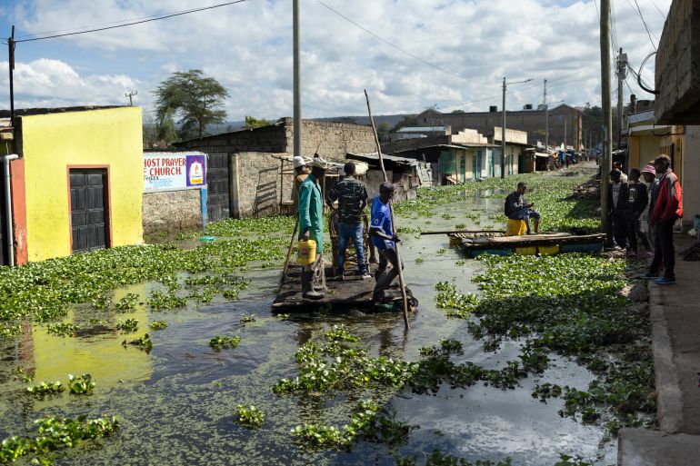 Residents use push poles to manuever their makeshift rafts over a flooded access road to their residential blocks at Kohoto estate in Naivasha on November 17, 2025.